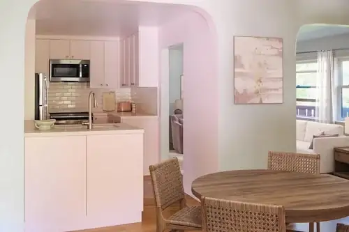 Berkeley kitchen remodel with pink walls, an arched doorway, white cabinets and a round wood breakfast table