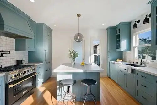 Berkeley kitchen remodel with blue-painted cabinets, white subway tile, a range hood in the same blue and an island with black stools