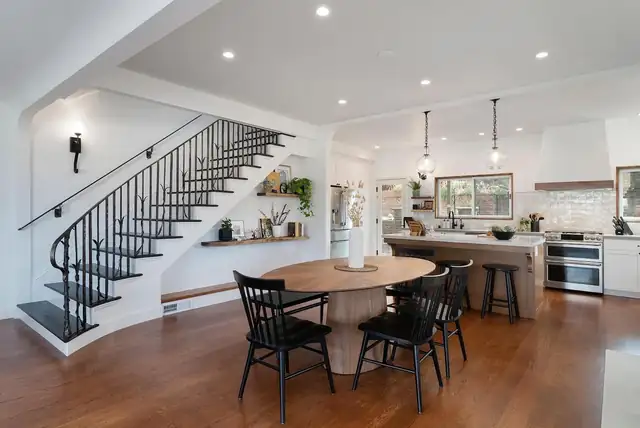 Oakland whole-home remodel joining the kitchen and dining room, with a round wood table, black spindle chairs and an open staircase